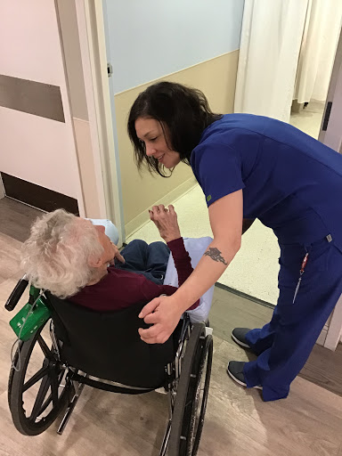 A compassionate nurse interacts with an elderly patient in a wheelchair, showcasing the importance of care in healthcare settings.