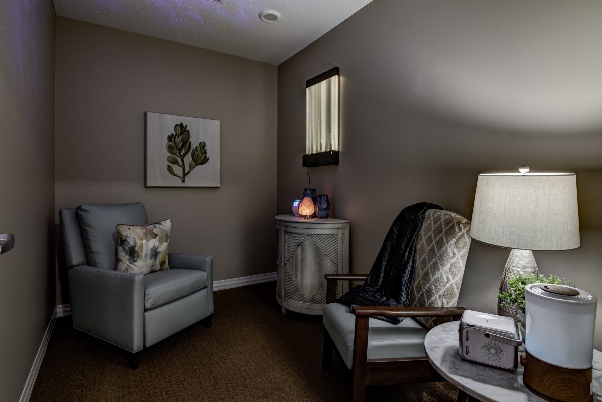 A cozy and elegantly designed living room corner featuring comfortable armchairs, a lamp, and soothing decor.