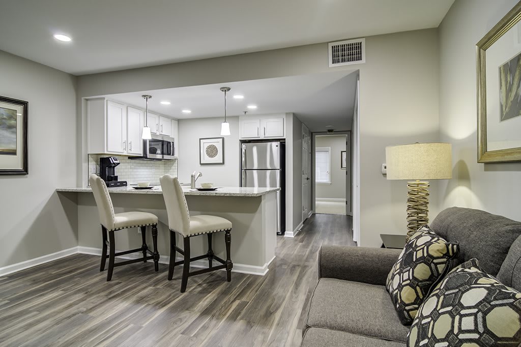 Modern open-concept living room and kitchen with neutral colors and stylish bar stools.