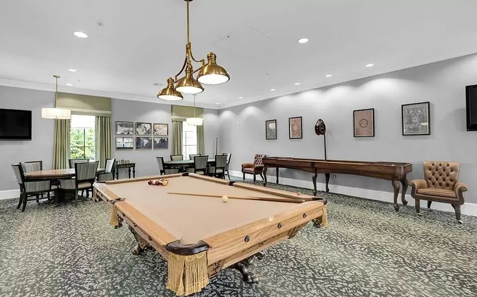 A well-lit billiards room with a pool table and seating area.