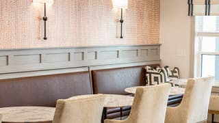 Cozy cafe seating area with tables, chairs, and wall lighting.