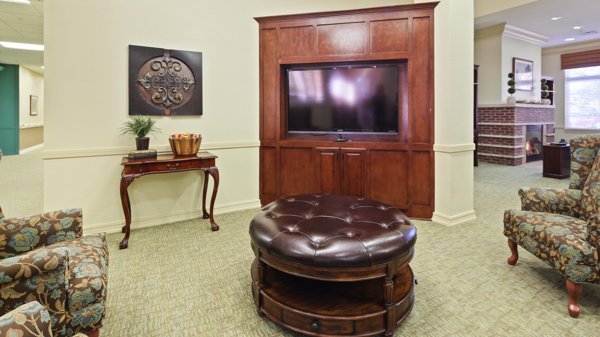 Cozy living room with a large TV and leather ottoman.