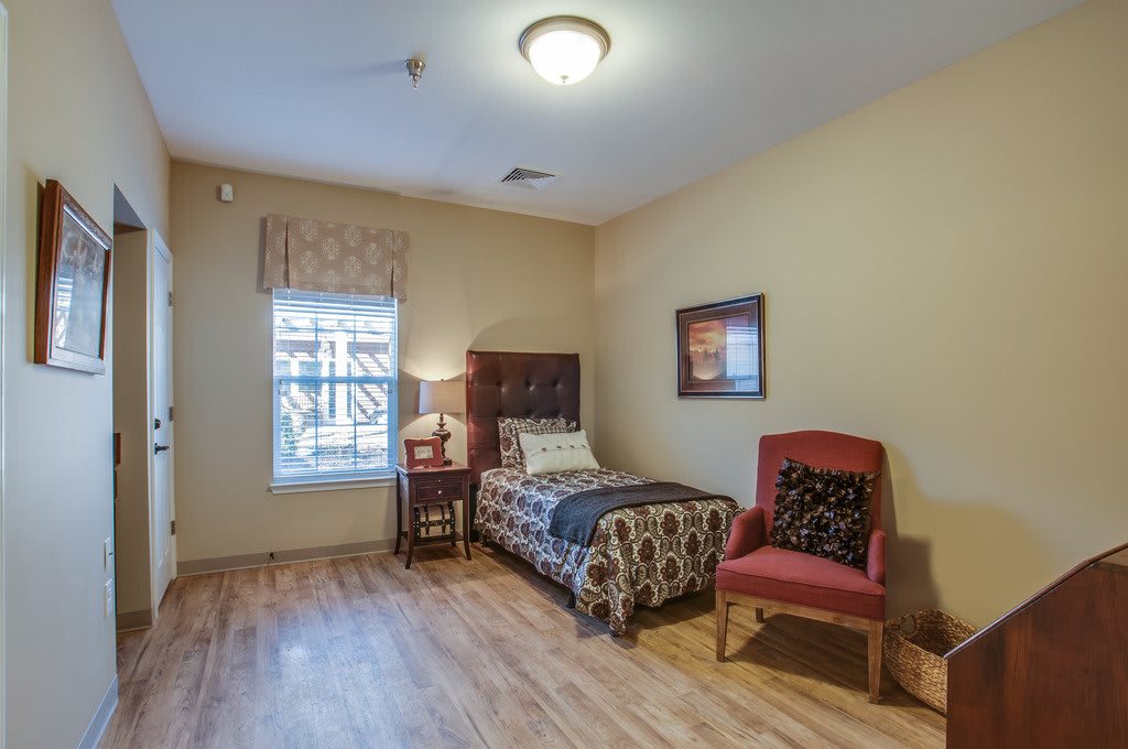 A cozy bedroom with a single bed, wooden flooring, and comfortable seating.
