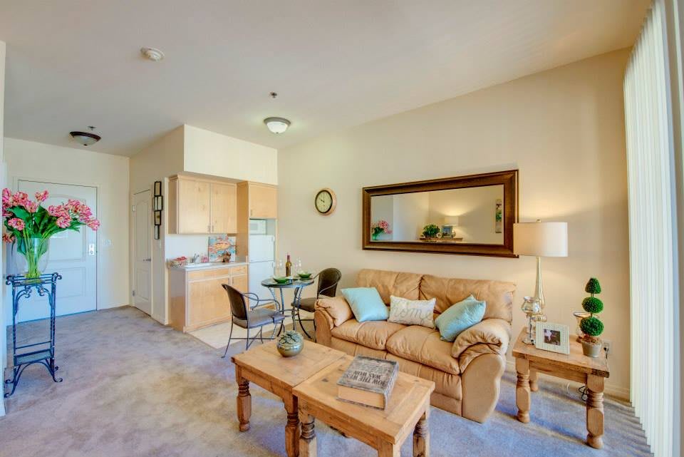 A cozy living room with a sofa, coffee table, and kitchenette in the background.