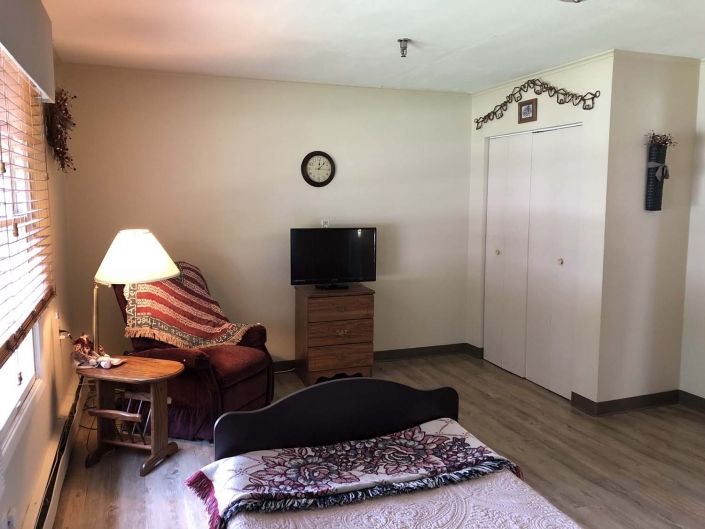 A cozy bedroom with a bed, television, and a comfortable chair.