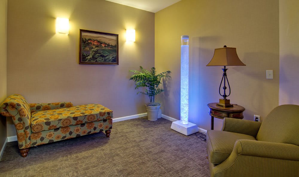 A cozy living room with modern decor, featuring a lamp, artwork on the wall, and a plant adding a touch of greenery.