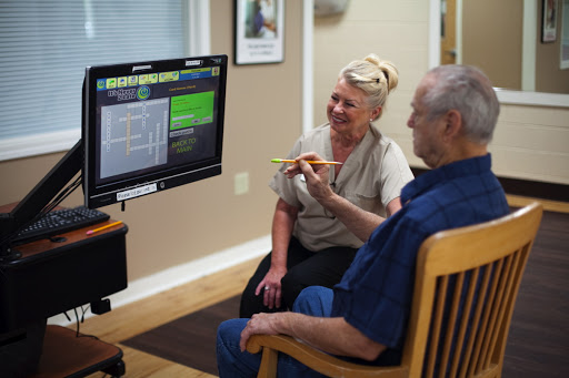 A healthcare professional engages with an elderly patient, utilizing technology for therapeutic purposes.