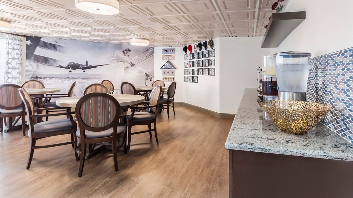 A cozy cafe interior with elegant round tables, chairs, and aviation-themed wall decor.