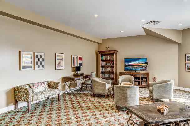 A cozy living room with comfortable seating, a bookshelf, and decorative artwork on the walls.