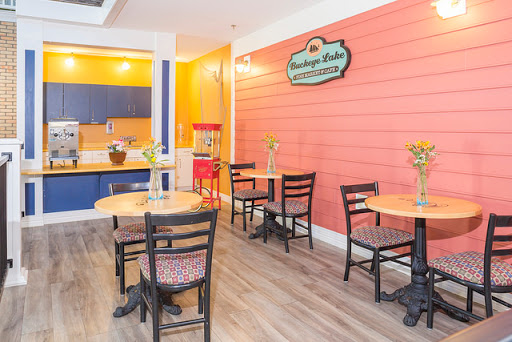 A cozy cafe featuring a vibrant orange wall, wooden tables, and comfortable seating.