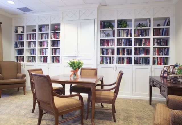 A cozy library setting with a table, chairs, and bookshelves.