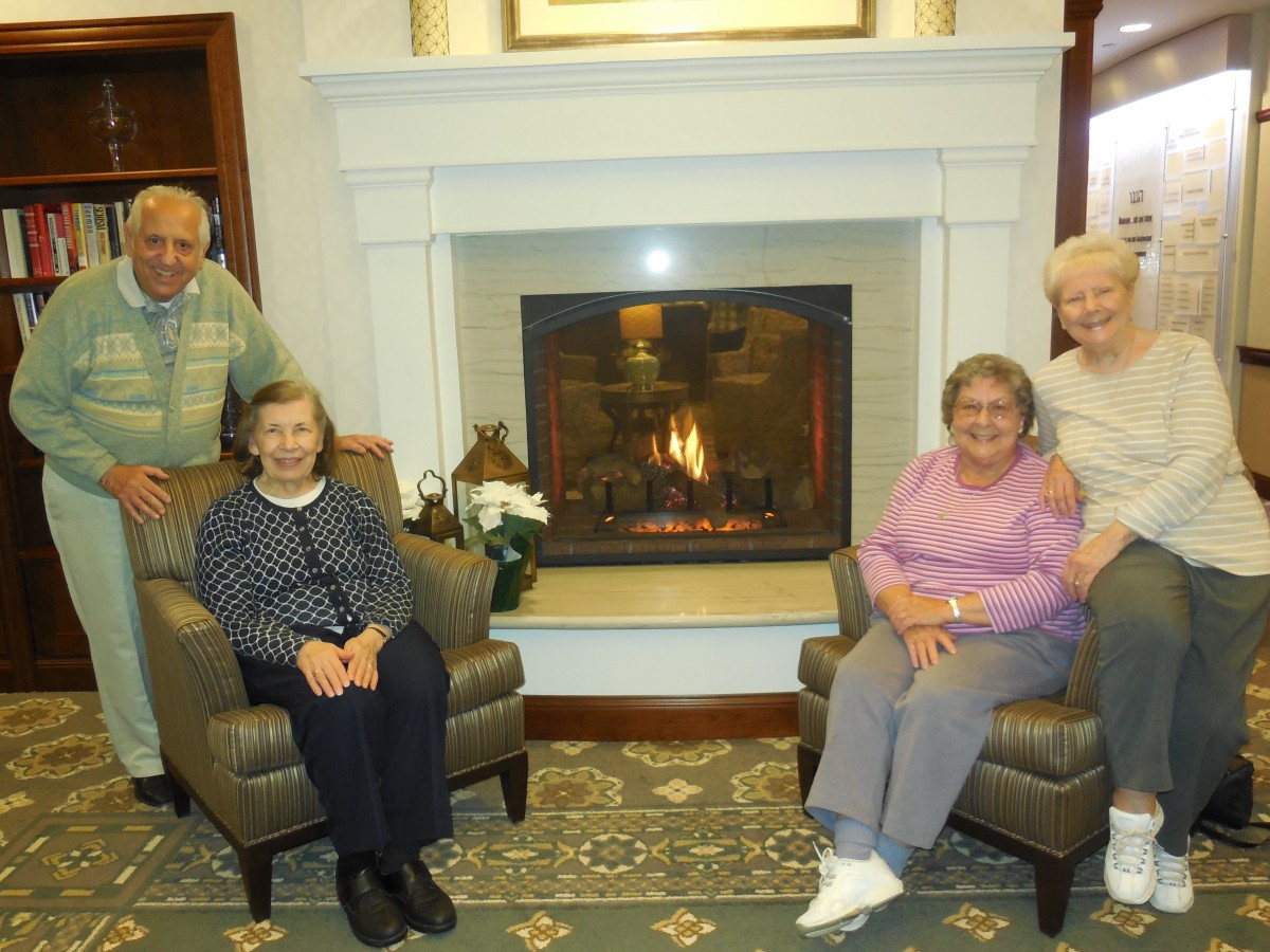 A group of elderly individuals seated around a fireplace.