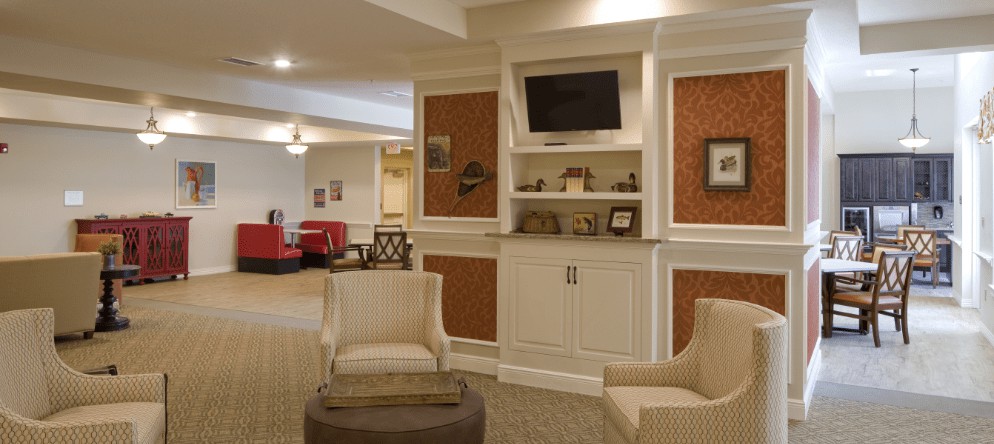 A cozy living room with elegant furniture and decor, featuring a mounted television and shelves.