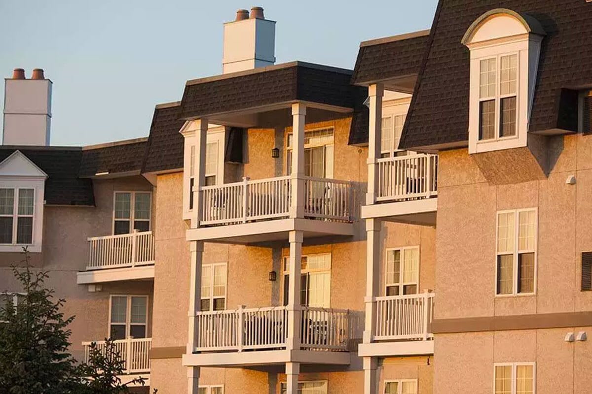 A view of an apartment building with multiple balconies at sunset.
