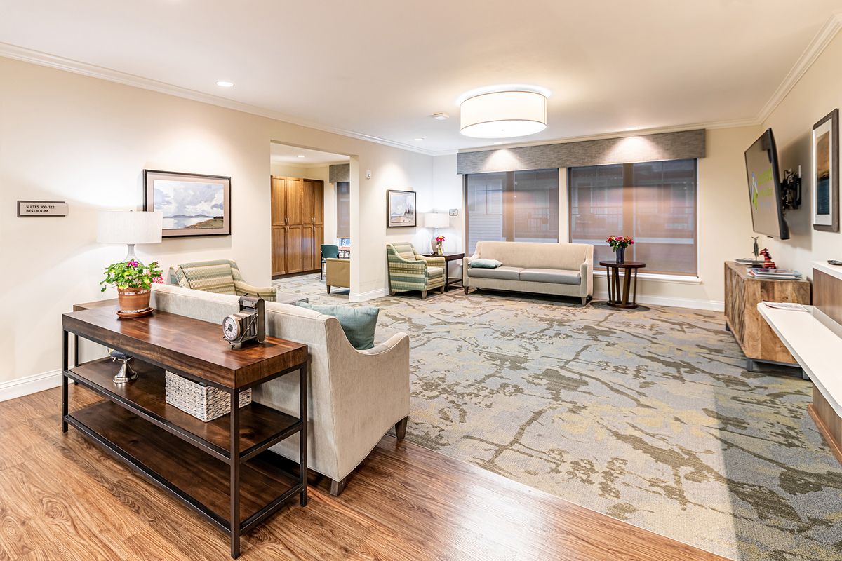 A spacious and cozy living room with modern decor, featuring comfortable sofas, a large patterned carpet, and elegant artwork on the walls.