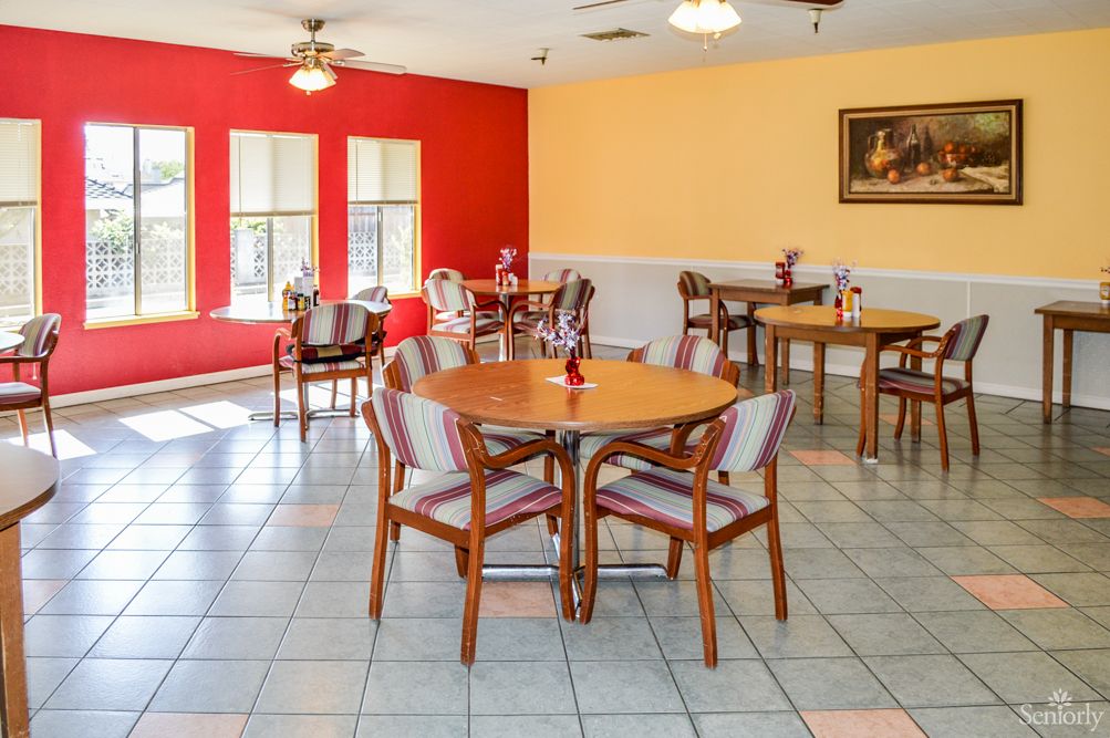 A bright dining area featuring multiple tables and chairs, with colorful walls and ceiling fans.
