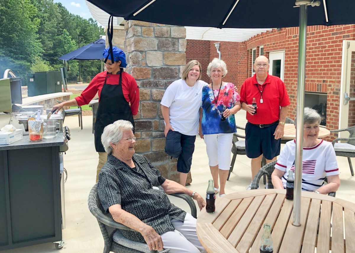 A group of seniors enjoying a social gathering under the patio umbrella.
