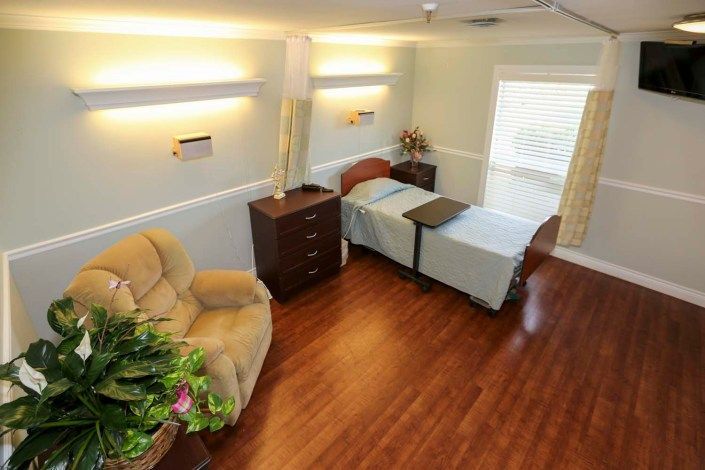 A cozy bedroom with wood flooring, featuring a single bed, chair, and tasteful decor.