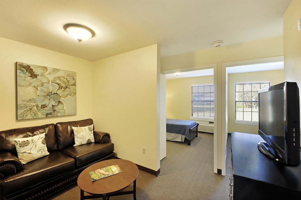 A cozy apartment interior featuring a living room with a sofa and coffee table, adjacent to a bedroom.