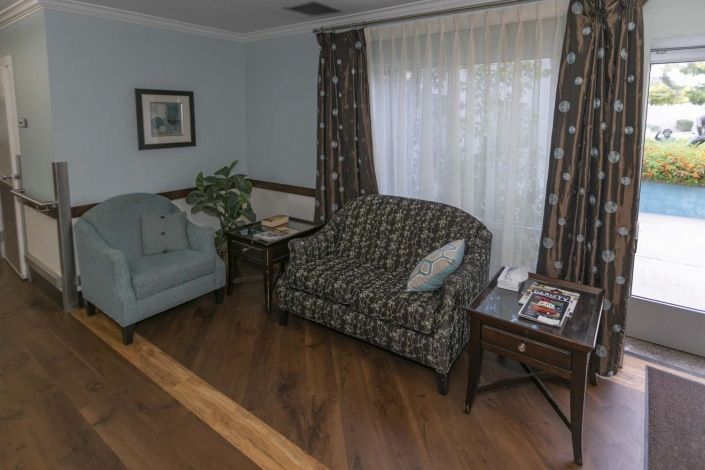 A cozy living room with a sofa, armchair, and wooden flooring.