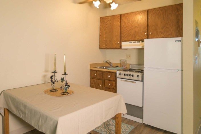 A compact kitchen with a dining table adorned with candles.