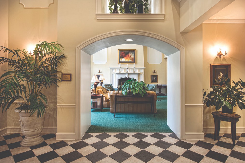 A cozy lobby featuring an archway entrance with a seating area and fireplace.