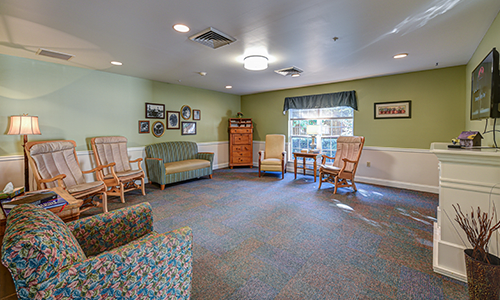 A cozy living room with sofas and chairs, featuring soft lighting and decor.