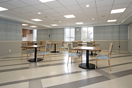 A spacious and modern dining area featuring wooden tables and chairs, illuminated by natural light from large windows.