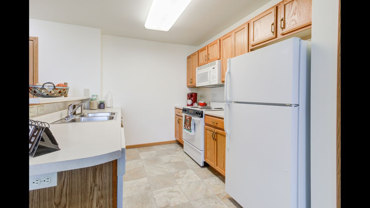 A neat kitchen with wooden cabinets and standard appliances.