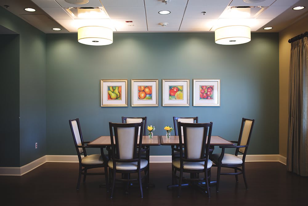 A modern dining room with a set table, contemporary artwork, and stylish overhead lighting.