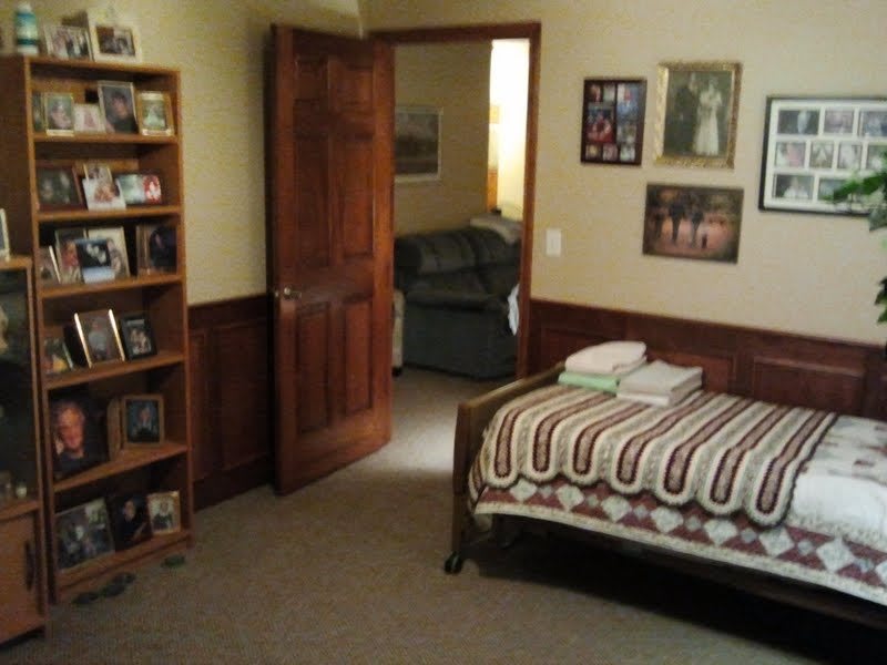 A cozy bedroom with a striped bedspread, wooden door, and decorative shelves.