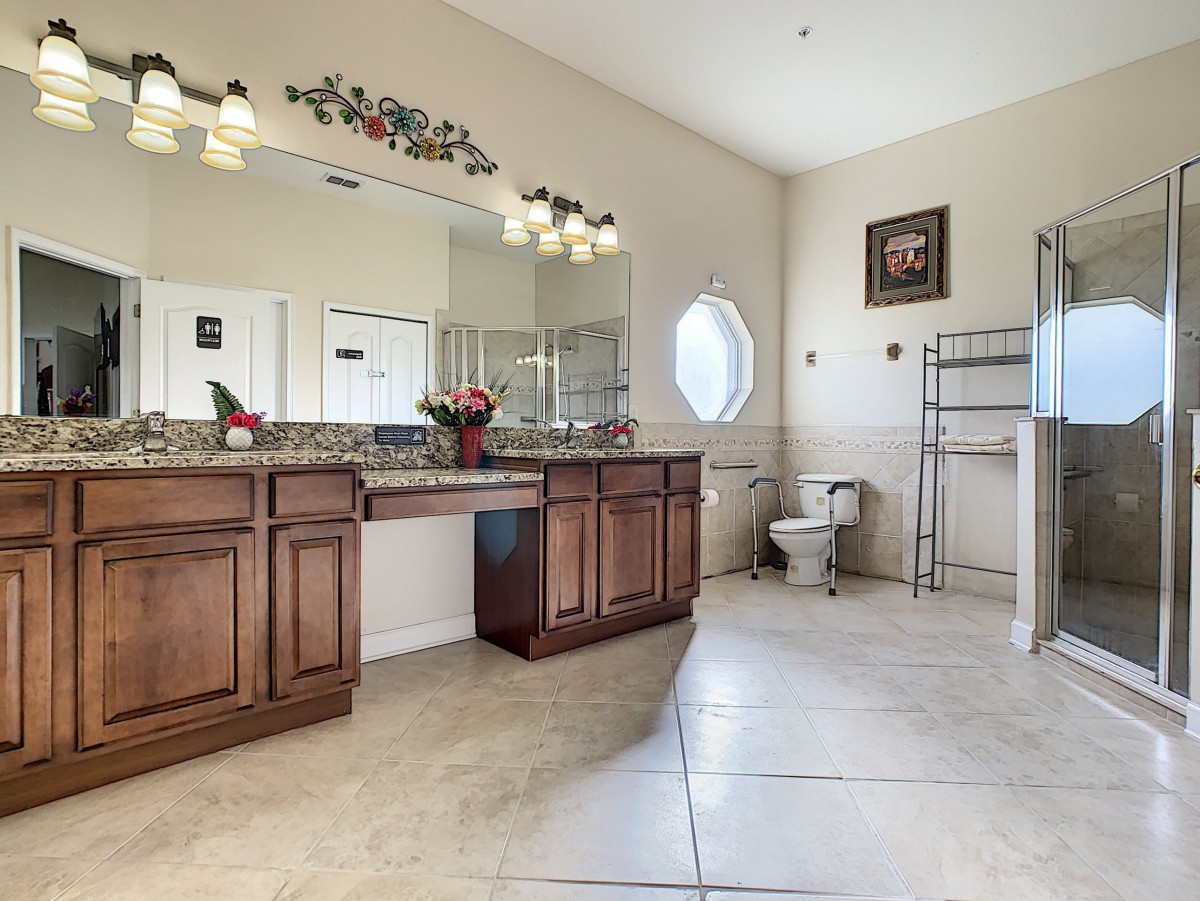 A spacious and elegantly designed bathroom featuring a large vanity with mirrors, decorative lighting, and tiled flooring.
