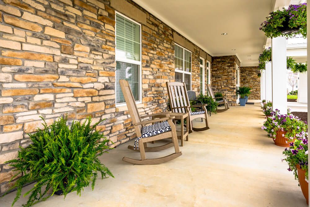 A cozy front porch with rocking chairs and a stone wall.