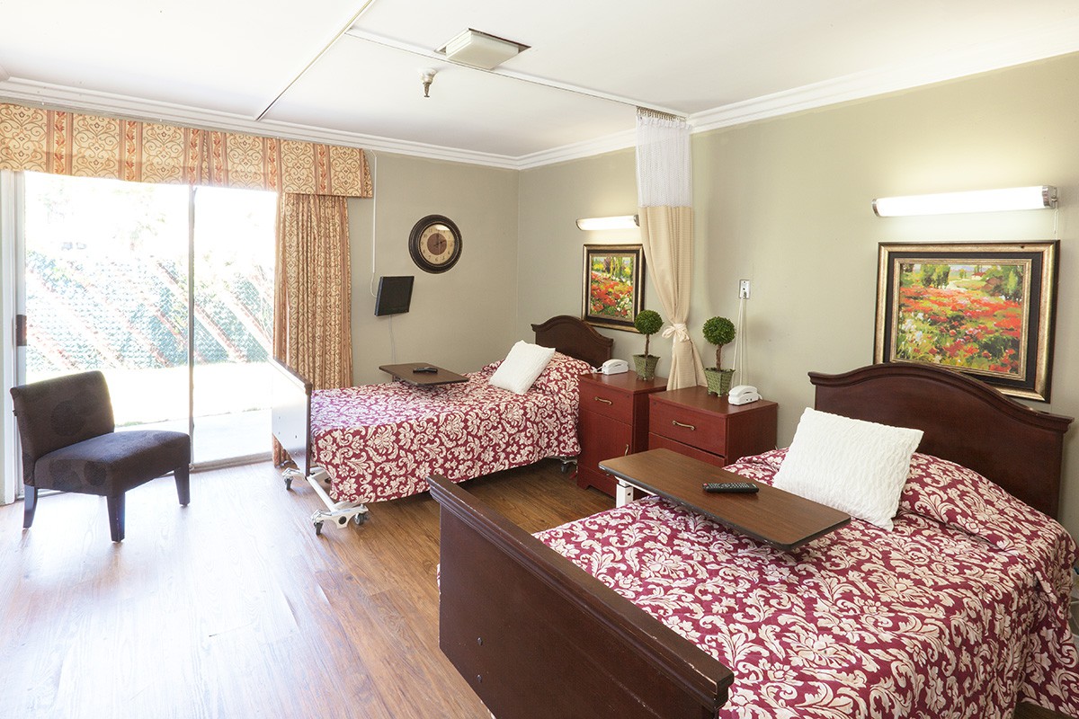 A shared hospital room with two neatly made beds and well-lit surroundings.