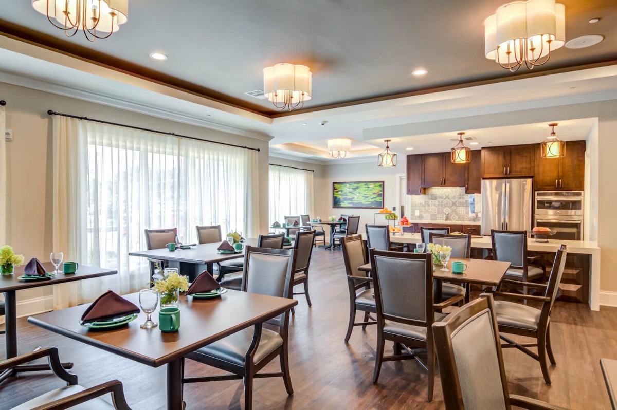 A spacious and elegantly designed dining room with neatly arranged tables and chairs, featuring modern lighting fixtures.