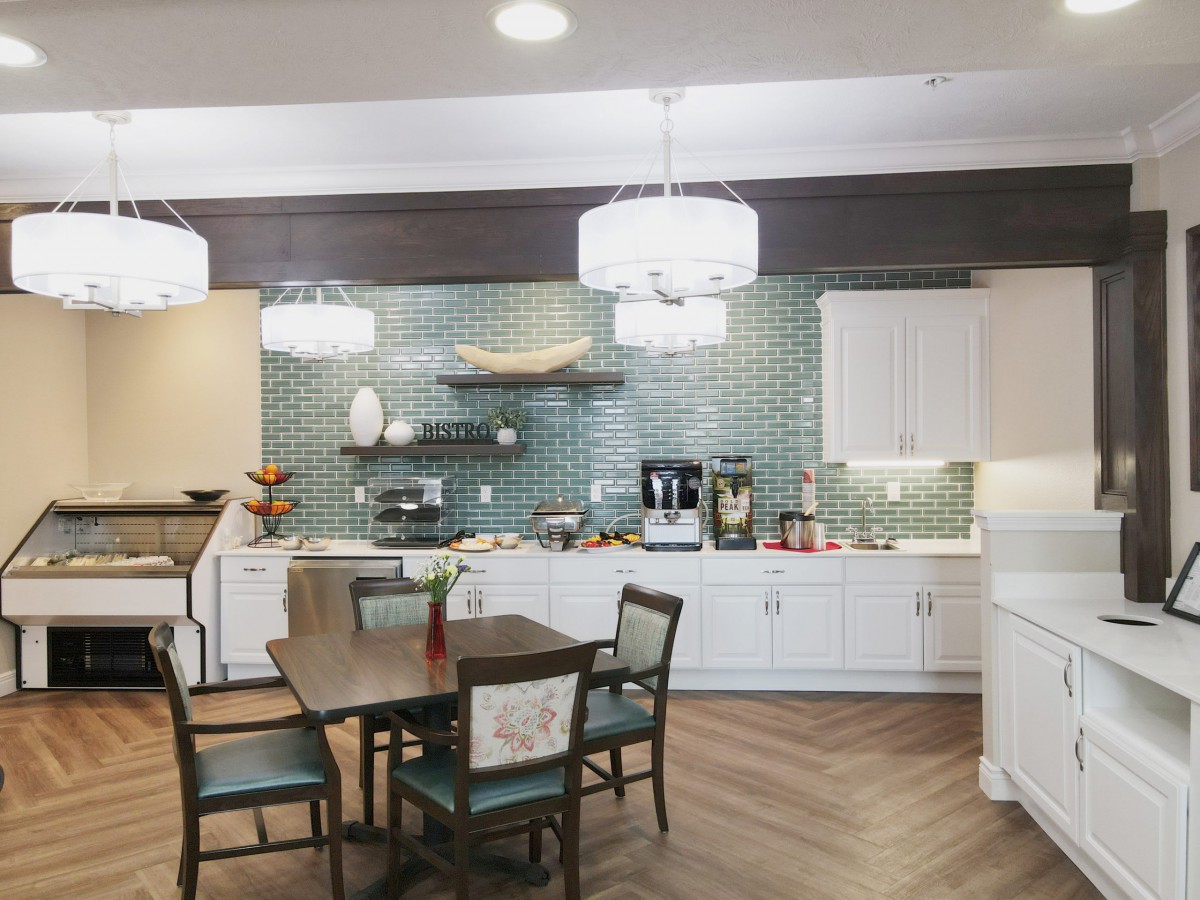 A modern kitchen and dining area with stylish lighting and a tiled backsplash.