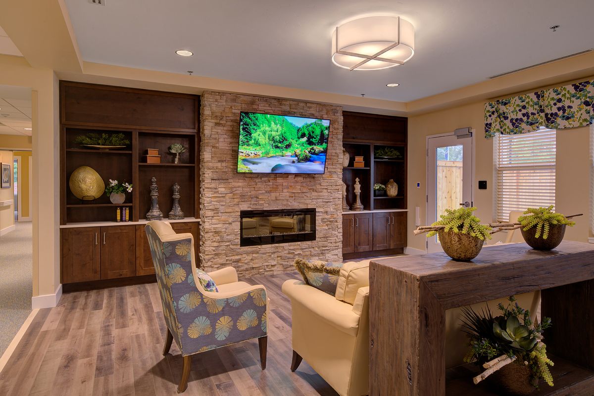 A modern living room with a fireplace and television, featuring cozy seating and stylish decor.