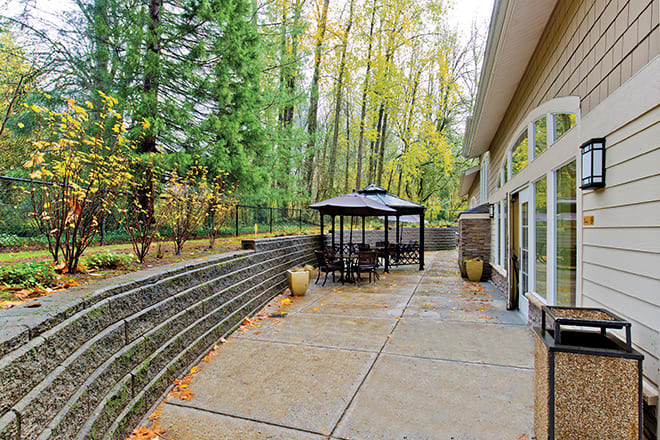 A spacious patio with a gazebo surrounded by a lush forest in autumn.