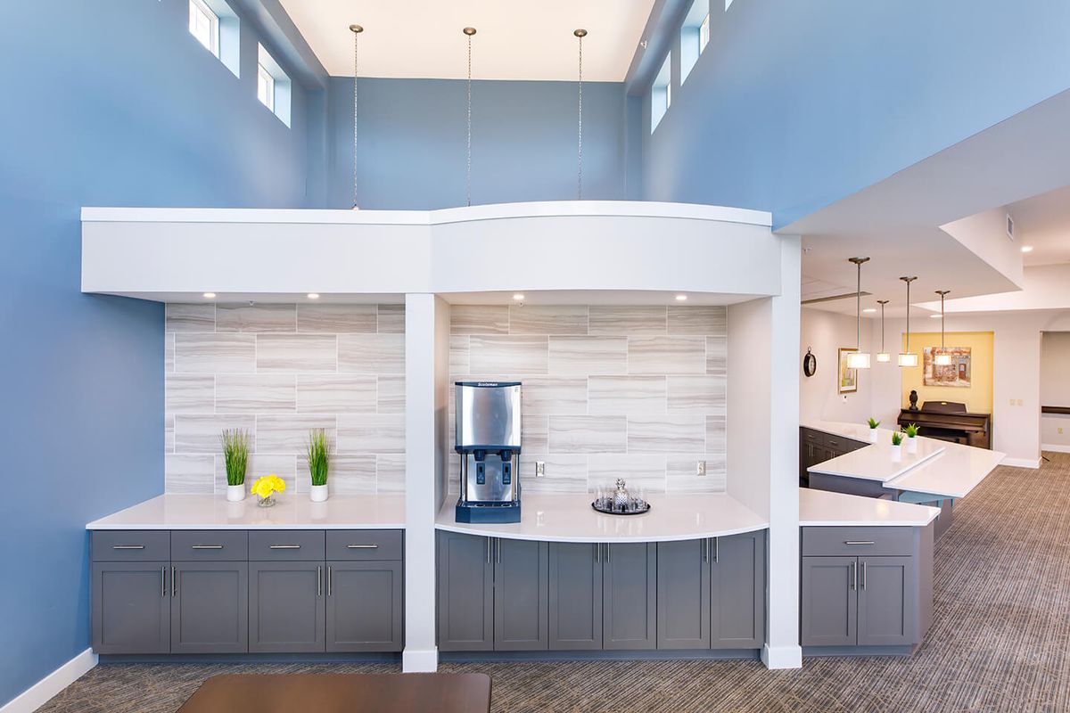 A modern kitchen with blue walls and sleek countertops, featuring contemporary lighting fixtures.
