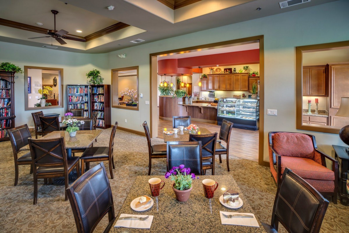 A cozy restaurant interior with neatly arranged tables and chairs, featuring a warm ambiance and decorative plants.