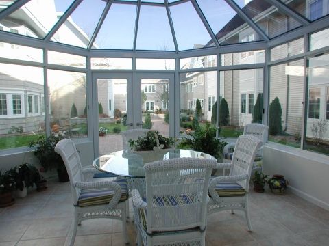 A bright conservatory with wicker furniture offers a cozy view of the garden.
