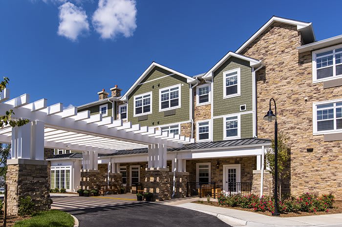 A modern residential building with a stone facade and white trim under a blue sky.