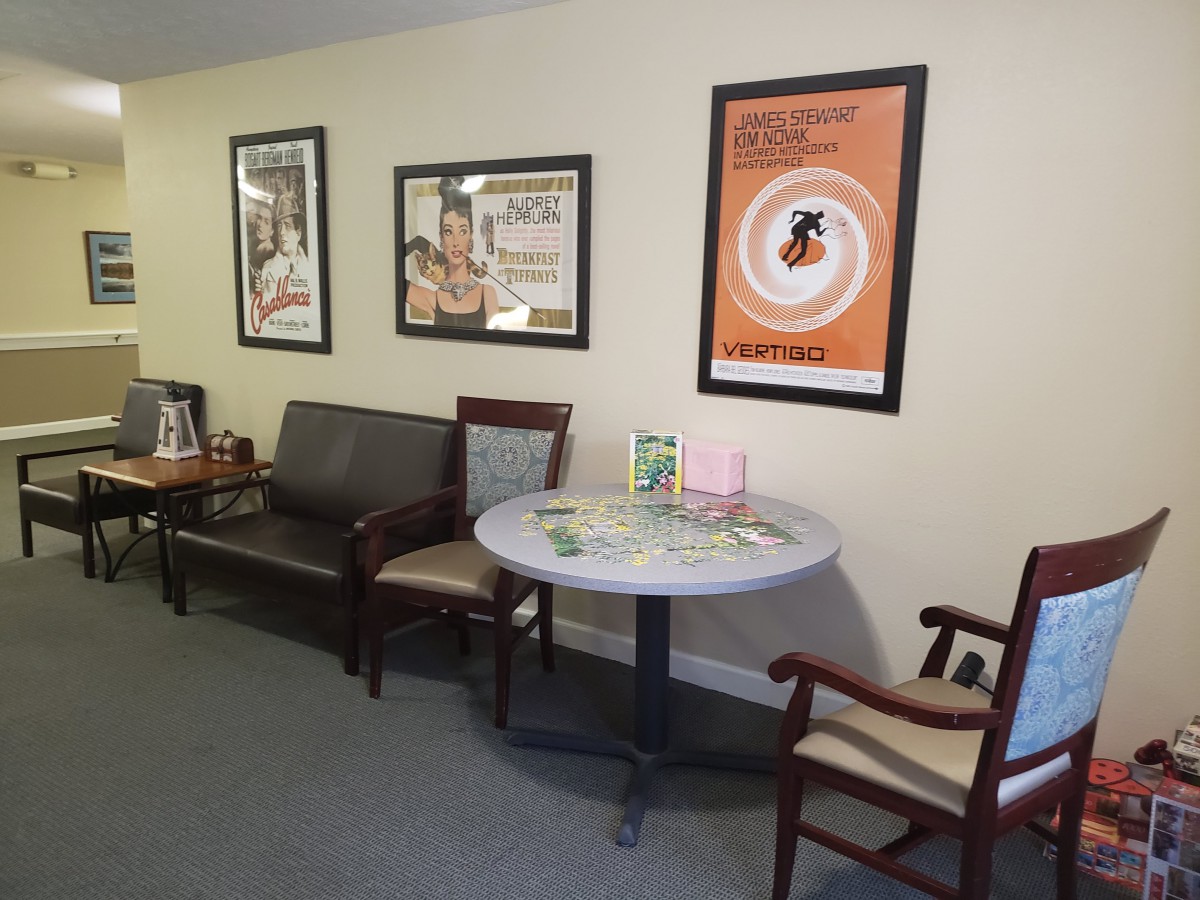 A cozy waiting room area with framed posters, chairs, and a small round table.