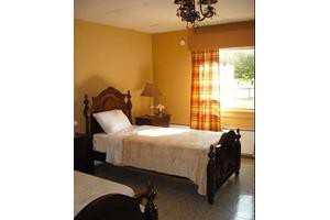 A cozy bedroom with a single bed, wooden furniture, and warm yellow walls.