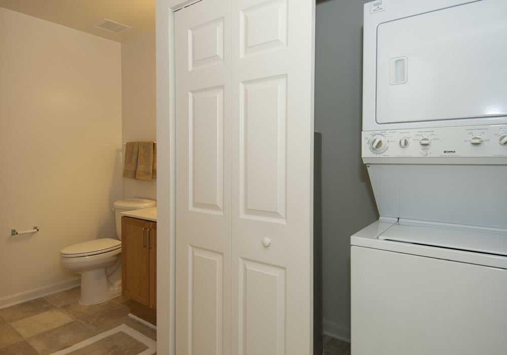 A view of a bathroom adjacent to a compact laundry area with a stacked washer and dryer.