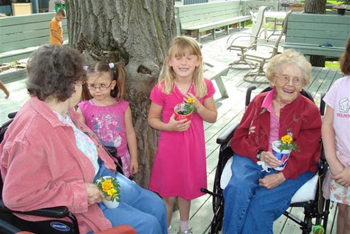 A joyful moment shared between children and elderly individuals, celebrating together with flowers.