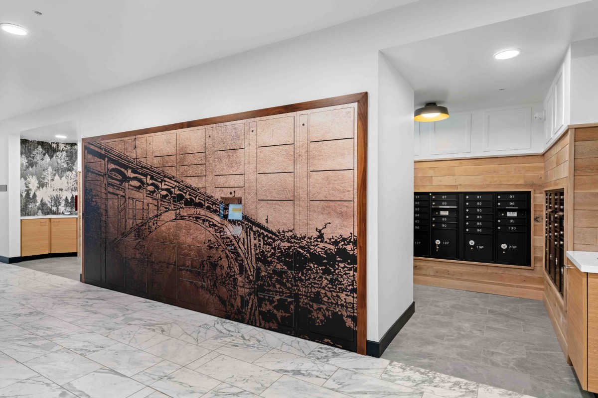 A modern lobby featuring a large artwork, marble flooring, and mailboxes.