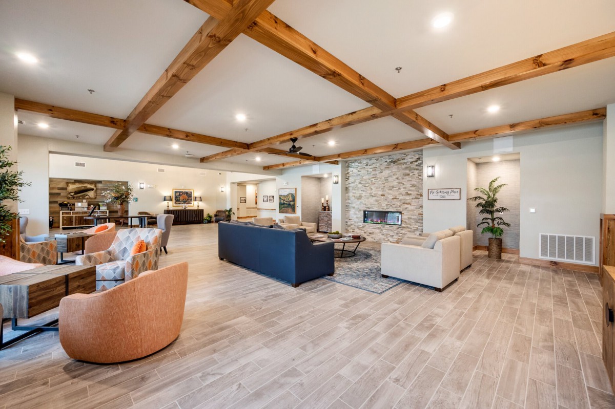 A spacious and modern living room with wooden beams, stylish furniture, and a central fireplace.