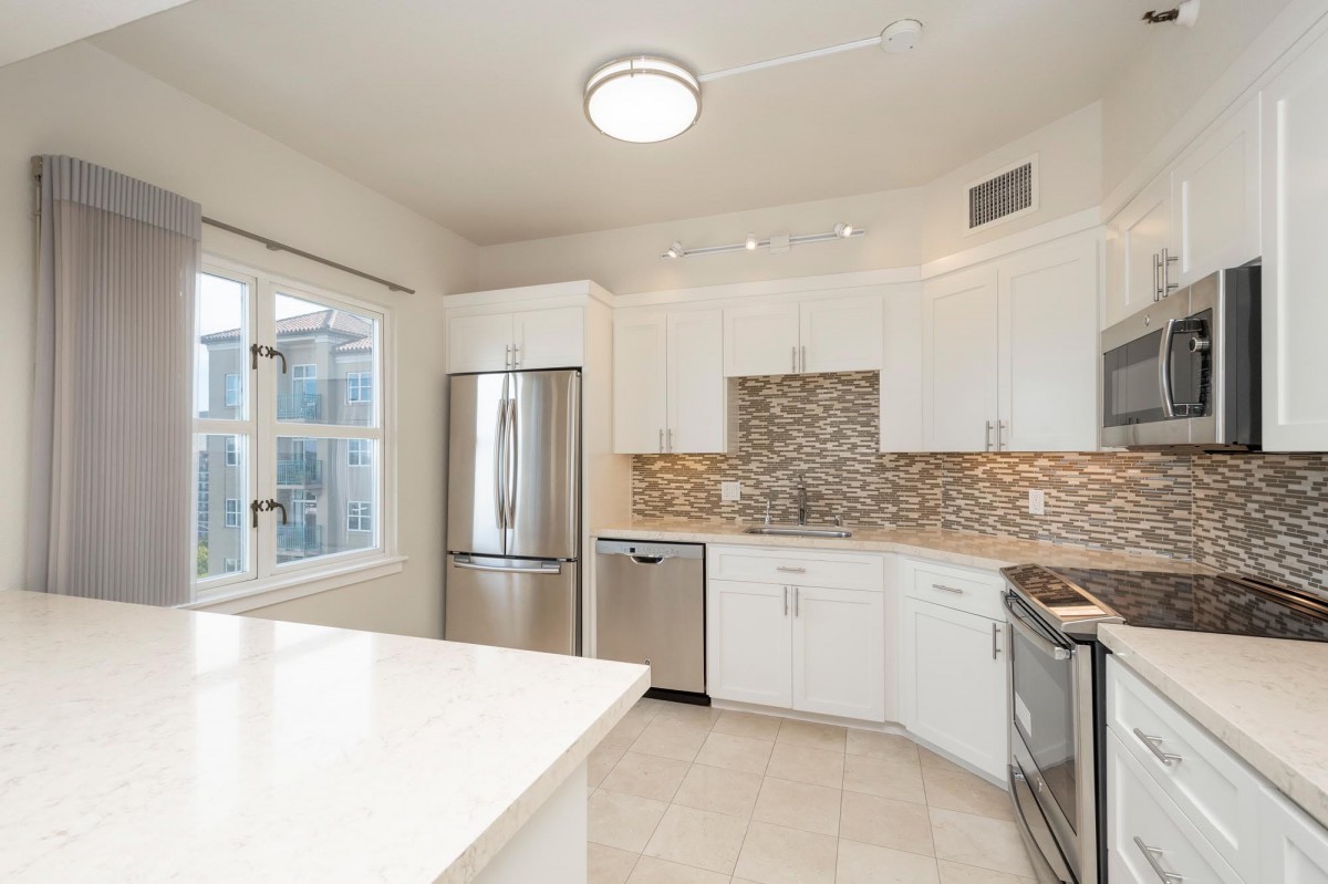 A modern kitchen with white cabinets, stainless steel appliances, and a decorative backsplash.