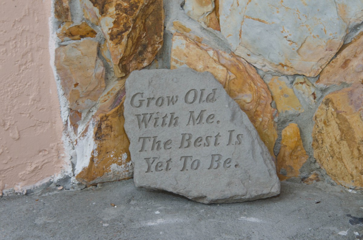A stone with the engraving 'Grow Old With Me. The Best Is Yet To Be.' leaning against a wall.